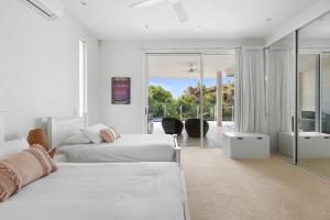 a white bedroom with two beds and a balcony at 7 on Pelican Street Peregeian Beach in Peregian Beach +30 photos