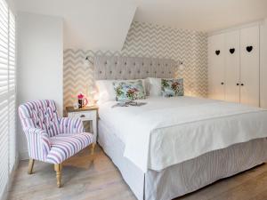 a bedroom with a white bed and a chair at The Dormouse -uk46926 in Newby Bridge