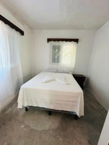 ein weißes Bett in einem Zimmer mit Fenster in der Unterkunft Casa Villa Pesca in Monterrico