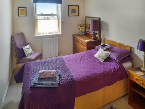 a bedroom with a purple bed and a chair at Lilac Cottage in Redmire