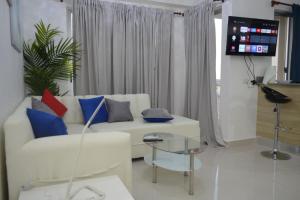 a living room with a white couch and a tv at Apartamento Marla Comodo y cerca del aeropuerto in Santo Domingo