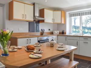 - une cuisine avec une table en bois et de la nourriture dans l'établissement Gymmin House, à Pendine