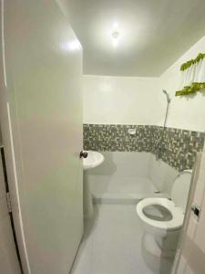 a white bathroom with a toilet and a sink at Tamari's Rest house (Small house) in Lian