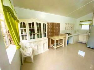 a kitchen with white cabinets and a table and a refrigerator at Tamari's Rest house (Small house) in Lian