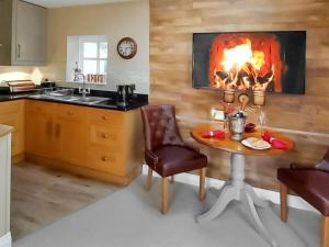 eine Küche mit einem Tisch und einem Kamin in der Unterkunft The Lodge in Llangelynin