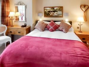 Schlafzimmer mit einem großen rosa Bett und einem Schreibtisch in der Unterkunft The Lodge in Llangelynin