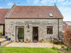 a stone house with a patio and a table at Chapel Barn - Uk46738 in Shapwick