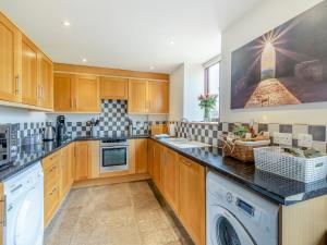 a kitchen with wooden cabinets and a washer and dryer at Chapel Barn - Uk46738 in Shapwick