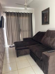 - un salon avec un canapé en cuir brun devant une fenêtre dans l'établissement Casa confortável, Temporada Votuporanga, à Votuporanga
