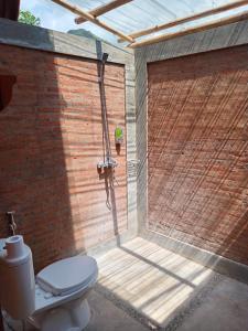 a bathroom with a toilet and a brick wall at Aisyah Villa Sumbawa in Maluk