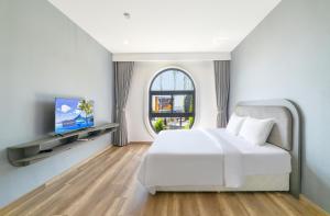 um quarto branco com uma cama e uma televisão em Hafi Boutique Hotel em Vung Tau
