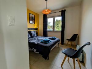 a bedroom with a bed and a chair and a window at Maison neuve et paisible avec étang privé, terrasse et randonnées aux portes du Pays de Salm - FR-1-589-635 in Moyenmoutier