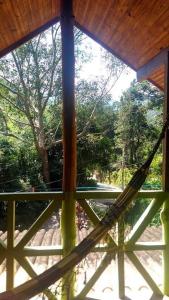hamak wiszący na drewnianym ganku z drzewem w obiekcie Casa da Cíntia w mieście Visconde De Maua