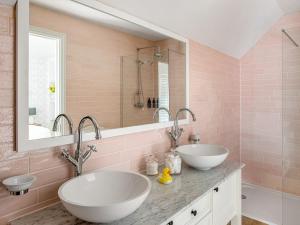 a pink bathroom with two sinks and a mirror at The Owl Nest-uk46927 in Newby Bridge