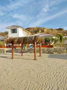 a hammock on the beach in front of a house at Casuarinas del Mar Chalet Playa Caballito de Mar in Canoas De Punta Sal