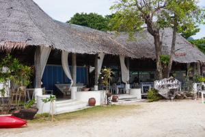 un ristorante con tetto di paglia e tavoli e sedie di Mayalay Resort-Green Hotel a Ko Ngai