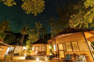 un groupe de maisons de nuit avec des palmiers dans l'établissement Mayalay Resort-Green Hotel, à Ko Ngai
