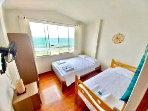 a bedroom with two beds and a window with the ocean at Casuarinas del Mar Chalet Playa Caballito de Mar in Canoas De Punta Sal