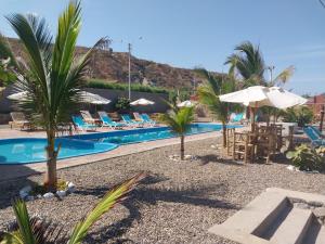 um resort com uma piscina com palmeiras e guarda-sóis em Casuarinas del Mar Chalet Playa Caballito de Mar em Canoas de Punta Sal