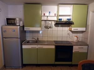 - une cuisine avec des placards verts et blancs et un évier dans l'établissement Ferienwohnung für 4 Personen ca 65 qm in Zelenka, Dalmatien Mitteldalmatien, à Makarska