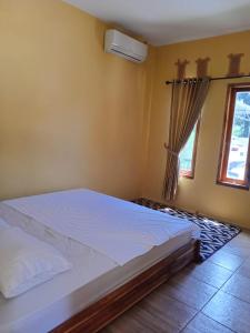 1 dormitorio con 1 cama blanca y ventana en Aisyah Villa Sumbawa, en Maluk