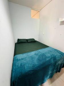 Bett in einem weißen Zimmer mit einer blauen Decke in der Unterkunft APTO Mobiliado Aconchegante Serra Cantareira Cod 1 in Caieiras