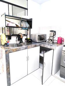 uma cozinha com armários brancos e um lavatório em "Pacae" House em Ica