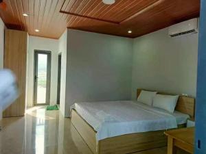Schlafzimmer mit einem Bett mit Holzdecke in der Unterkunft Biển Xanh Homestay in Ly Son