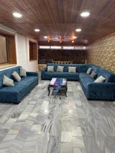 uma grande sala de estar com sofás azuis e uma mesa em شقه فخمه مفروشه بالكامل في اربد em Irbid