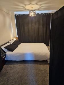 a bedroom with a bed with a black curtain at Cosy Hadleigh in Hadleigh