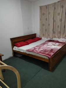 a bedroom with a bed with red pillows and a window at Traveler's Choice in Nuwara Eliya