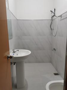 a white bathroom with a sink and a shower at Traveler's Choice in Nuwara Eliya