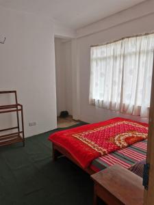 ein Schlafzimmer mit einem Bett mit einer roten Bettdecke und einem Fenster in der Unterkunft Traveler's Choice in Nuwara Eliya