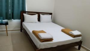 um quarto com uma cama com lençóis brancos e almofadas em Tamora By avea em Madurai
