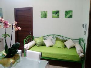 ein grünes Sofa mit Kissen in einem Zimmer mit Tisch in der Unterkunft Studio für 3 Personen ca 40 qm in Alcamo, Sizilien Nordküste von Sizilien in Alcamo