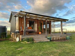 a small house with a porch and a deck at Romantic hilltop hideaway - Skyview Cottage in Dairy Flat