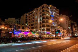 a city street at night with buildings and lights at Pebbles Boutique Aparthotel in Sliema