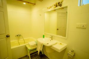 a bathroom with a sink and a mirror and a tub at Trinco Beach by DSK in Trincomalee