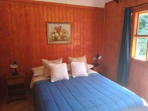 a bedroom with a blue bed with a red wall at Cabaña Palual in El Manzano