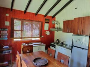 a kitchen with a wooden table and a white refrigerator at Cabaña Palual in El Manzano