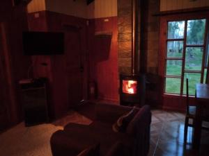 a living room with a couch and a fire place at Cabaña Palual in El Manzano