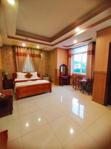 een grote slaapkamer met een bed en een tafel bij Quoc Dung Hotel in Rach Gia