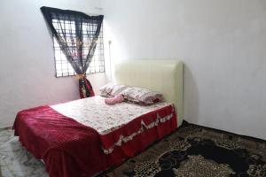 Schlafzimmer mit einem Bett mit roter Bettwäsche und einem Fenster in der Unterkunft Singgahan Cinta Iris in Kampong Gong Merbau