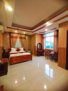 een slaapkamer met een bed en een tafel en stoelen bij Quoc Dung Hotel in Rach Gia
