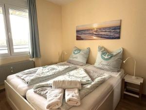 ein Bett mit Handtüchern darauf in einem Schlafzimmer in der Unterkunft Haus "Aquamarina", Wohnung 45 in Heiligenhafen