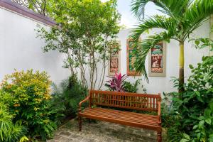 una panchina di legno in un giardino con alberi e piante di Angam Suites Colombo a Sri Jayewardenepura Kotte