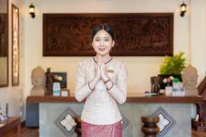 kobieta stojąca w pokoju z rękami w medytacji w obiekcie Two Seasons Siem Reap Hotel w Siem Reap