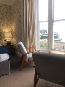 a bedroom with a bed and a chair and a window at Helmsman Guesthouse in Aberystwyth