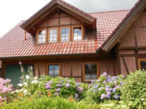 una casa con techo rojo y algunas flores en Ferienwohnung Kribitz, en Hodenhagen