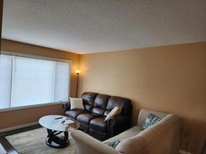 sala de estar con sofá de cuero y mesa en Beautiful updated home centrally located, close to General Hospital en Regina